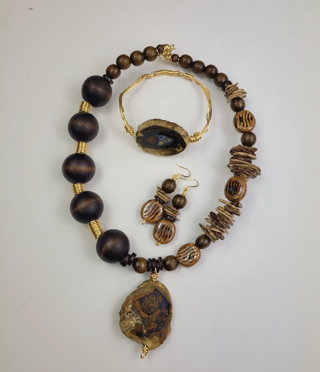 Chunky dark brown wood beaded necklace with gold spacers and a rustic agate slab pendant, paired with a gold wire bracelet and drop earrings.