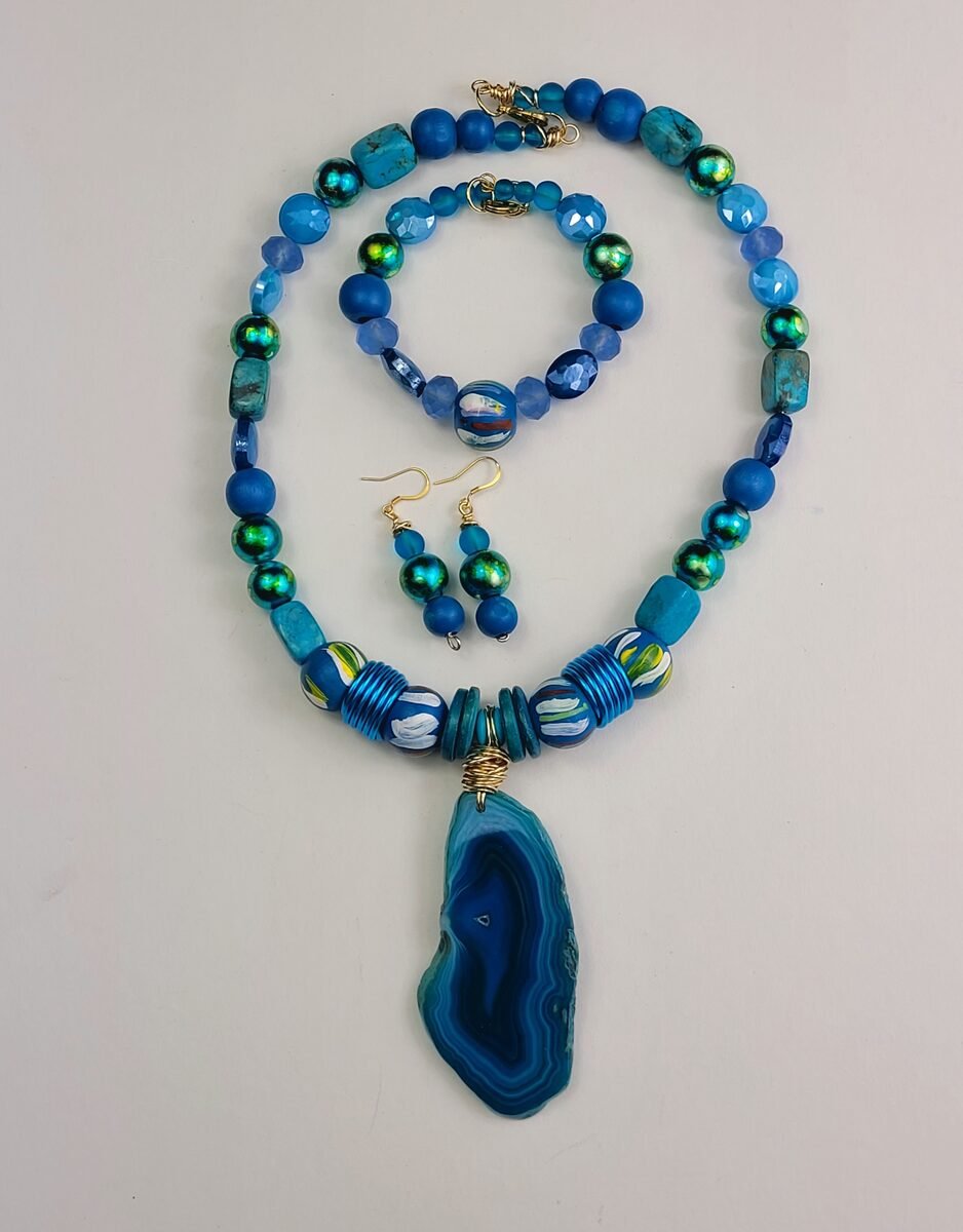 Ocean blue beaded necklace with iridescent green crystal spacers and a blue agate slice pendant.